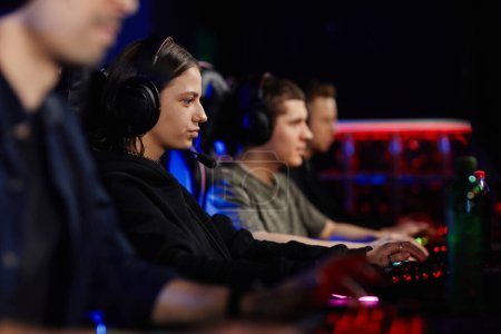 Foto de Retrato de vista lateral de una joven enfocada jugando videojuegos con un equipo de ciberdeporte en la oscuridad - Imagen libre de derechos