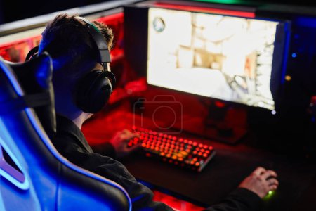 Foto de Hombre irreconocible jugando videojuegos en la oscuridad sentado en la silla de juego, concepto de eSports - Imagen libre de derechos