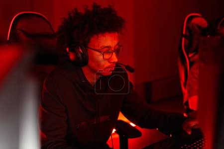 Photo for Portrait of young African American man playing video games in red neon light - Royalty Free Image