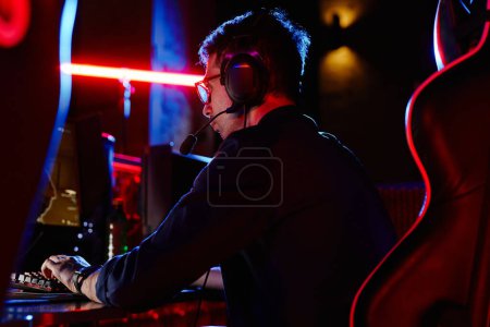 Photo for Low angle view at adult man playing video games in dark with neon accents, copy space - Royalty Free Image