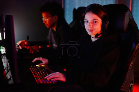 Photo for Portrait of female gamer looking at camera in red neon light and smiling, copy space - Royalty Free Image