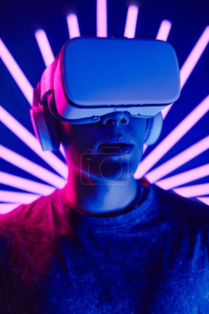 Foto de Retrato vertical futurista de un joven con auriculares VR con haces de luz de neón en el fondo - Imagen libre de derechos