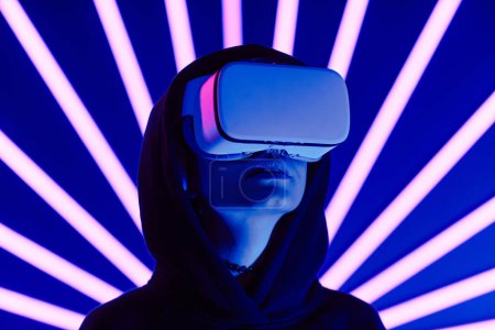 Téléchargez les photos : Plan futuriste d'une jeune femme portant un casque VR avec des faisceaux lumineux au néon en arrière-plan, espace de copie - en image libre de droit