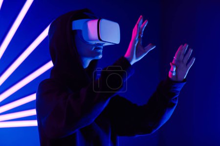 Téléchargez les photos : Plan futuriste d'une jeune femme portant un casque VR en 3 dimensions avec des faisceaux lumineux au néon, espace de copie - en image libre de droit