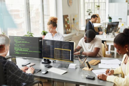 Photo for Group of programmers working in team with new project at table behind the window at office - Royalty Free Image
