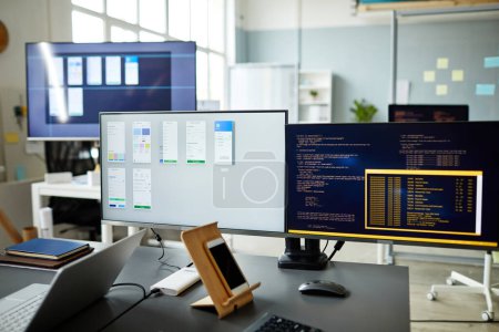 Foto de Imagen horizontal de monitores de ordenador con programas y códigos de ordenador en monitores de pie en el lugar de trabajo del programador - Imagen libre de derechos