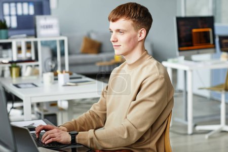 Téléchargez les photos : Jeune homme travaillant comme programmeur, écrivant du code de programmation sur ordinateur dans l'espace de coworking - en image libre de droit