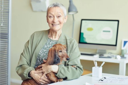 Téléchargez les photos : Portrait de femme âgée souriante avec petit chien dans une clinique vétérinaire regardant la caméra avec bonheur, espace de copie - en image libre de droit