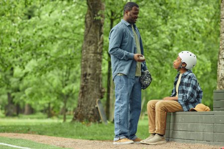 Téléchargez les photos : Papa africain parlant à son fils avant de s'entraîner au baseball dans le parc - en image libre de droit