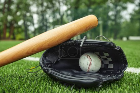 Téléchargez les photos : Vue rapprochée de la balle de baseball en cuir blanc et du gant avec batte sur le terrain vert pour le match de baseball - en image libre de droit