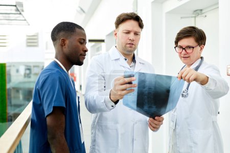 Foto de Retrato de cintura hacia arriba de diversos grupos de médicos que miran la imagen de rayos X en la clínica moderna, espacio para copiar - Imagen libre de derechos