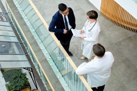 Photo for Graphic top down view at doctors discussing case while standing at balcony of modern clinic - Royalty Free Image