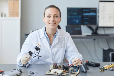Téléchargez les photos : Portrait d'une jeune femme souriante en tant qu'ingénieure regardant la caméra tout en travaillant dans un laboratoire, copiez l'espace - en image libre de droit