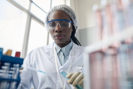 Foto de Retrato de una científica negra con gafas protectoras mientras hace experimentos en laboratorio - Imagen libre de derechos