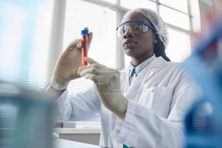 Téléchargez les photos : Portrait d'une scientifique noire tenant une éprouvette tout en faisant des expériences en laboratoire médical - en image libre de droit