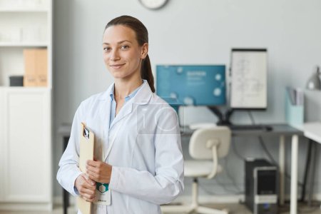 Photo for Waist up portrait of young female scientist wearing lab coat and smiling at camera, copy space - Royalty Free Image