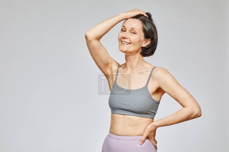 Photo for Minimal waist up portrait of carefree mature woman wearing neutral underwear against grey background, body positivity concept, copy space - Royalty Free Image