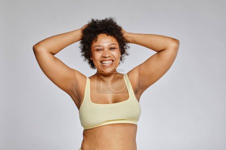 Photo for Minimal waist up portrait of carefree black woman wearing underwear and laughing happily against grey background - Royalty Free Image