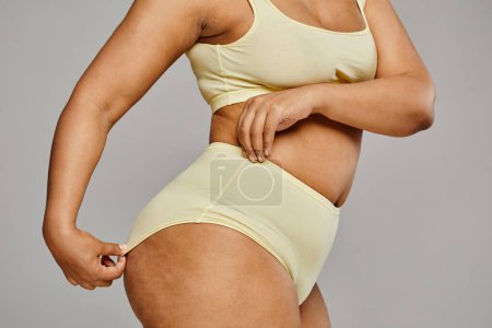Photo for Minimal cropped shot of unrecognizable black woman wearing underwear against grey background, focus on hips and cellulite, body positivity - Royalty Free Image