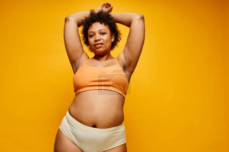 Foto de Retrato de la cintura hacia arriba de la mujer negra confiada que usa ropa interior contra el fondo amarillo vibrante, espacio de copia - Imagen libre de derechos