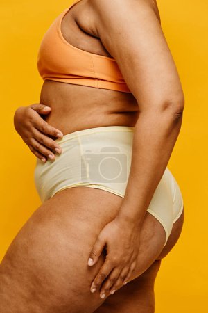Foto de Retrato vertical de vista lateral de una mujer negra real que usa ropa interior contra un fondo amarillo vibrante - Imagen libre de derechos