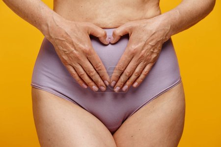 Téléchargez les photos : Gros plan de la femme portant des sous-vêtements tenant doucement les mains sur le ventre dans la région de l'utérus - en image libre de droit
