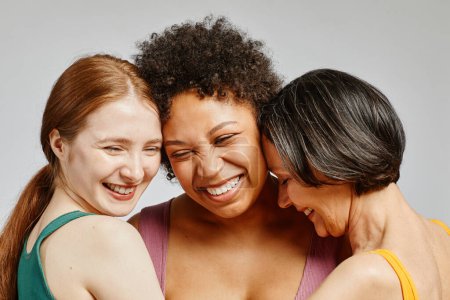 Ehrliches Porträt dreier unterschiedlicher junger Frauen, die fröhlich miteinander lachen
