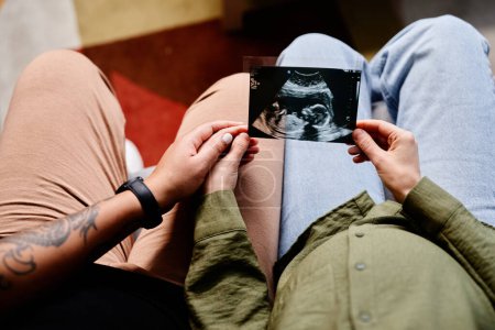 Téléchargez les photos : Gros plan du couple gay tatoué avec une jeune femme enceinte regardant l'image échographique du bébé, famille de même sexe - en image libre de droit
