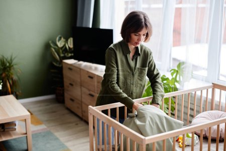 Téléchargez les photos : Portrait de jeune femme enceinte préparant un berceau à la maison, espace de copie - en image libre de droit