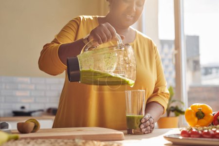 Téléchargez les photos : Photo ensoleillée de femme noire souriante profitant d'un smoothie sain à la cuisine de la maison, espace de copie - en image libre de droit