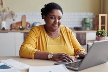 Téléchargez les photos : Sourire jeune femme noire faisant des affaires tout en travaillant à la maison - en image libre de droit