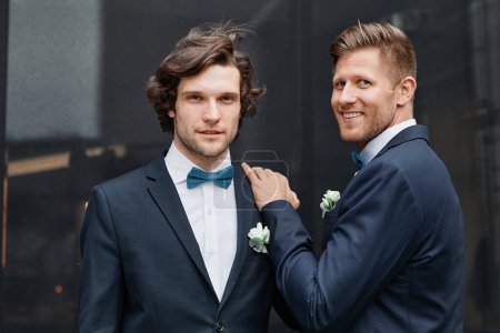 Foto de Cintura hacia arriba retrato de sonriente pareja del mismo sexo mirando a la cámara durante la ceremonia de boda - Imagen libre de derechos