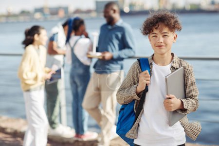 Téléchargez les photos : Portrait taille haute d'adolescent souriant avec sac à dos posant pendant les cours en plein air, espace de copie - en image libre de droit