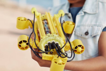Téléchargez les photos : Gros plan d'un enfant méconnaissable tenant un modèle de robot jaune, ingénierie pour enfants arrière-plan - en image libre de droit