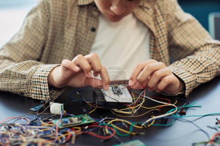 Photo for Close up of boy building robot and wiring circuit board during engineering class at school - Royalty Free Image