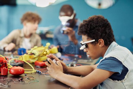 Foto de Retrato de vista lateral de un joven niño negro construyendo robots en clase de ingeniería en la escuela, espacio para copiar - Imagen libre de derechos