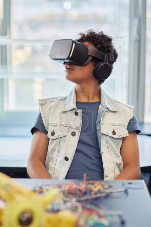 Photo for Vertical portrait of black teenage boy using VR technology in engineering class and looking around - Royalty Free Image
