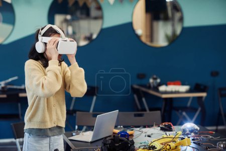 Foto de Retrato de cintura hacia arriba de una joven adolescente usando tecnología VR en clase de ingeniería en la escuela, espacio para copiar - Imagen libre de derechos