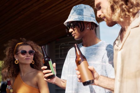 Foto de Diverso grupo de tres jóvenes disfrutando de refrescantes bebidas al aire libre en verano iluminados por la luz del sol - Imagen libre de derechos