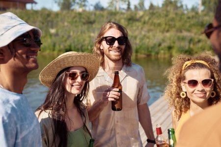 Téléchargez les photos : Groupe de jeunes tenant des bouteilles tout en profitant des vacances d'été au soleil - en image libre de droit