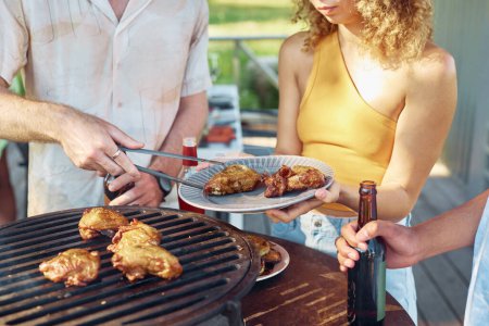 Téléchargez les photos : Gros plan d'amis faisant griller de la viande de poulet pendant la soirée barbecue en plein air en été - en image libre de droit