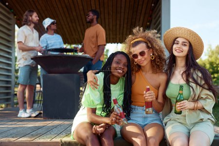 Foto de Diverso grupo de chicas mirando a la cámara mientras disfruta de la fiesta al aire libre con amigos en la cabina de verano, espacio para copiar - Imagen libre de derechos