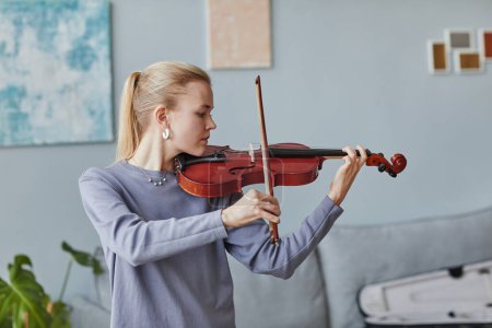 Foto de Retrato de cintura mínima hacia arriba de una joven tocando el violín en casa o en un estudio de música, espacio para copiar - Imagen libre de derechos
