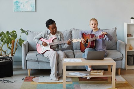 Photo for Minimal full length portrait of two young women playing guitar together in studio and composing music, copy space - Royalty Free Image