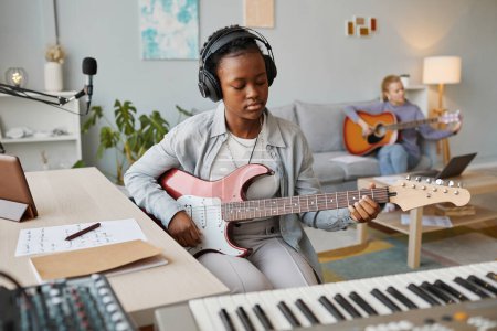 Photo for Portrait of young black woman playing electric guitar in studio and composing music, copy space - Royalty Free Image