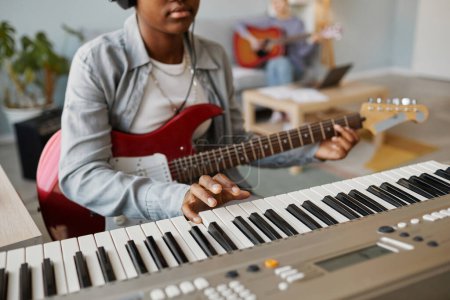 Téléchargez les photos : Gros plan de la jeune femme noire appuyant sur la touche piano tout en composant de la musique à la maison, espace de copie - en image libre de droit