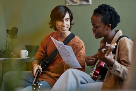 Téléchargez les photos : Portrait minimal d'un jeune couple souriant jouant de la musique ensemble et composant des chansons - en image libre de droit