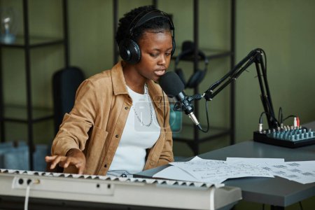 Téléchargez les photos : Portrait de jeune femme noire chantant au microphone tout en enregistrant de la musique à la maison - en image libre de droit
