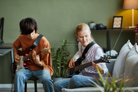 Téléchargez les photos : Portrait de jeune femme blonde jouant de la guitare et composant de la musique avec un jeune groupe de musiciens - en image libre de droit
