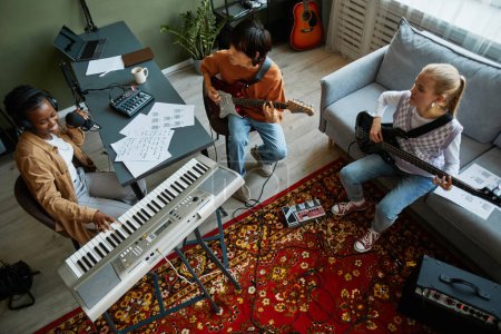 Foto de Vista superior en la banda de jóvenes músicos tocando instrumentos juntos en acogedor estudio en casa - Imagen libre de derechos